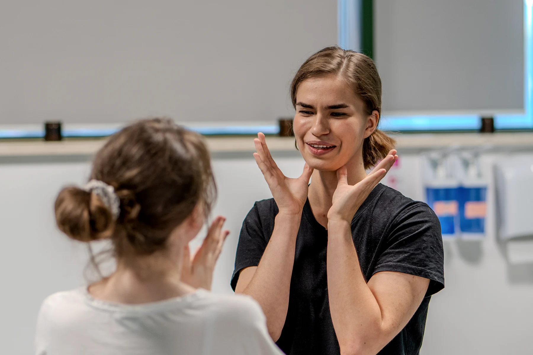 Fizjoterapia stomatologiczna w M&M Zdrowy Masaż — fizjoterapeutka Kasia pokazuje pacjentce ułożenie dłoni przy żuchwie