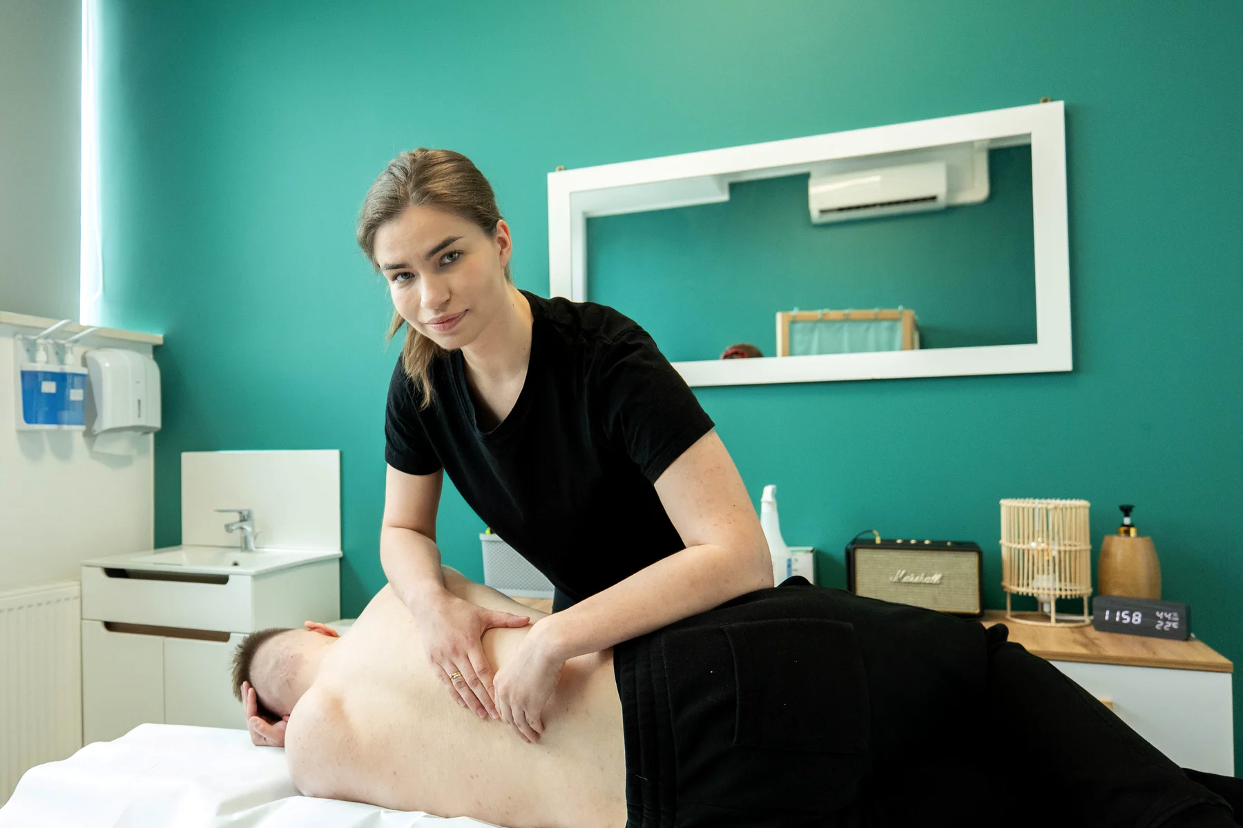 Terapia manualna w M&M Zdrowy Masaż — fizjoterapeutka opracowuje mięśnie pleców pacjenta leżącego na kozetce